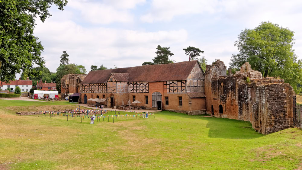 View of the ruins of Kenilworth Castle with a well-preserved stable on a sunny day