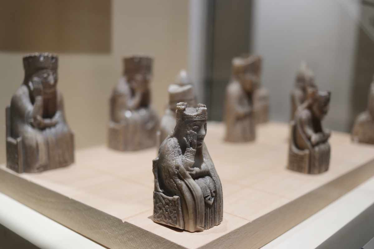 Several small, carved stone figures of seated, crowned individuals are displayed on a light-colored platform.