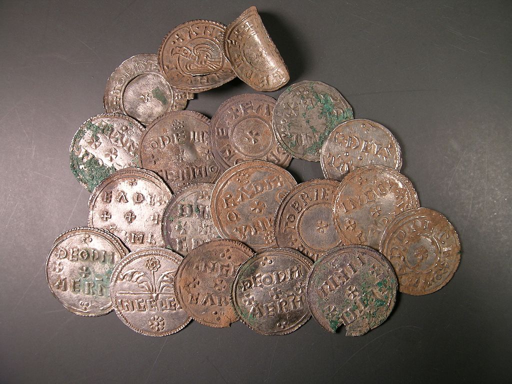 A collection of weathered, circular silver coins with stamped text and symbols arranged on a dark surface.