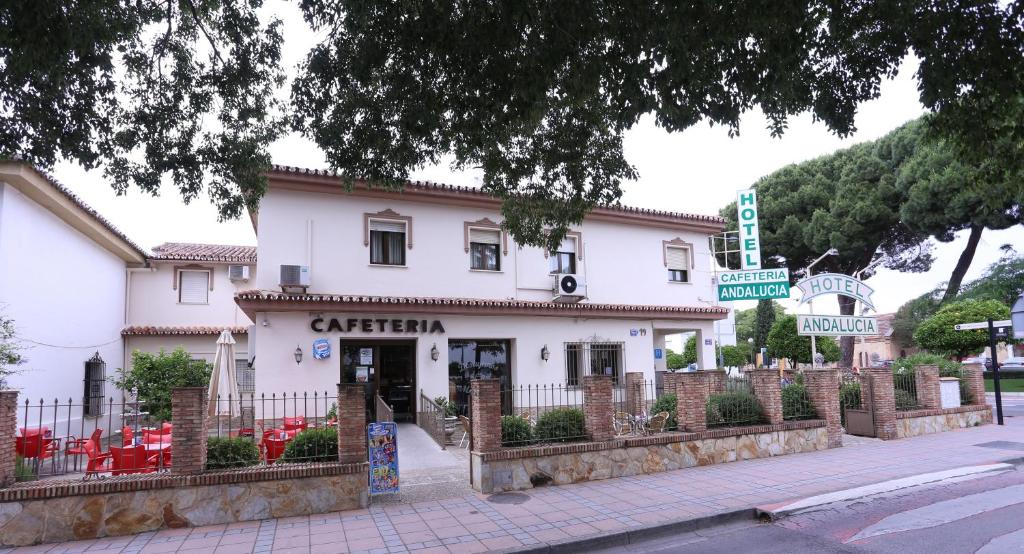 A two-story building labeled Hotel Andalucia with an outdoor cafeteria seating area behind a low stone and iron fence.