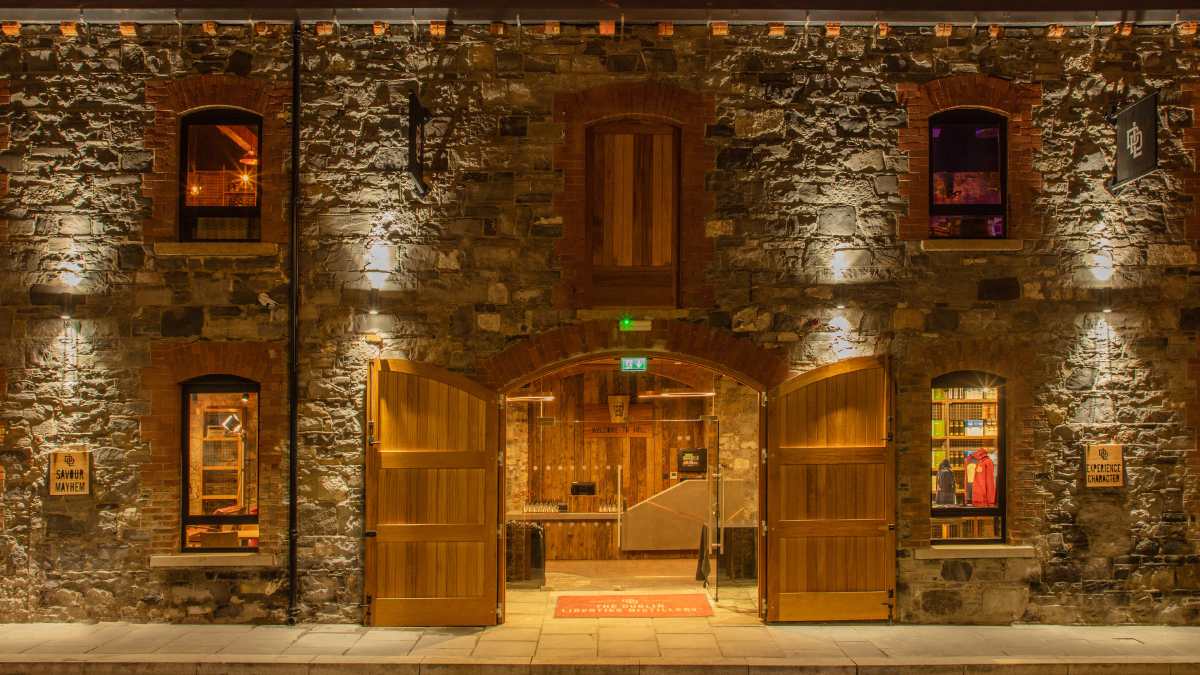 A stone building with arched wooden doors and illuminated windows at night.