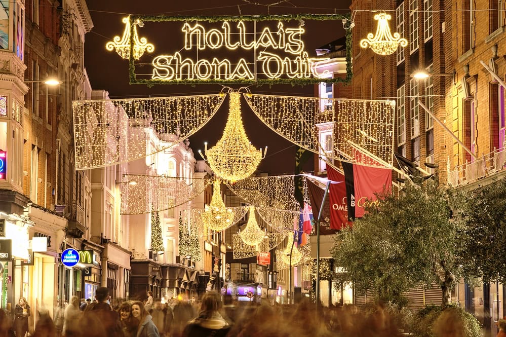 Dublin, Ireland - November 13. 2021: Beautiful evening view of Nollaig shona dhuit Christmas lights. Merry Christmas signboard written in Irish (Gaelic) language on Grafton Street. Crowded street