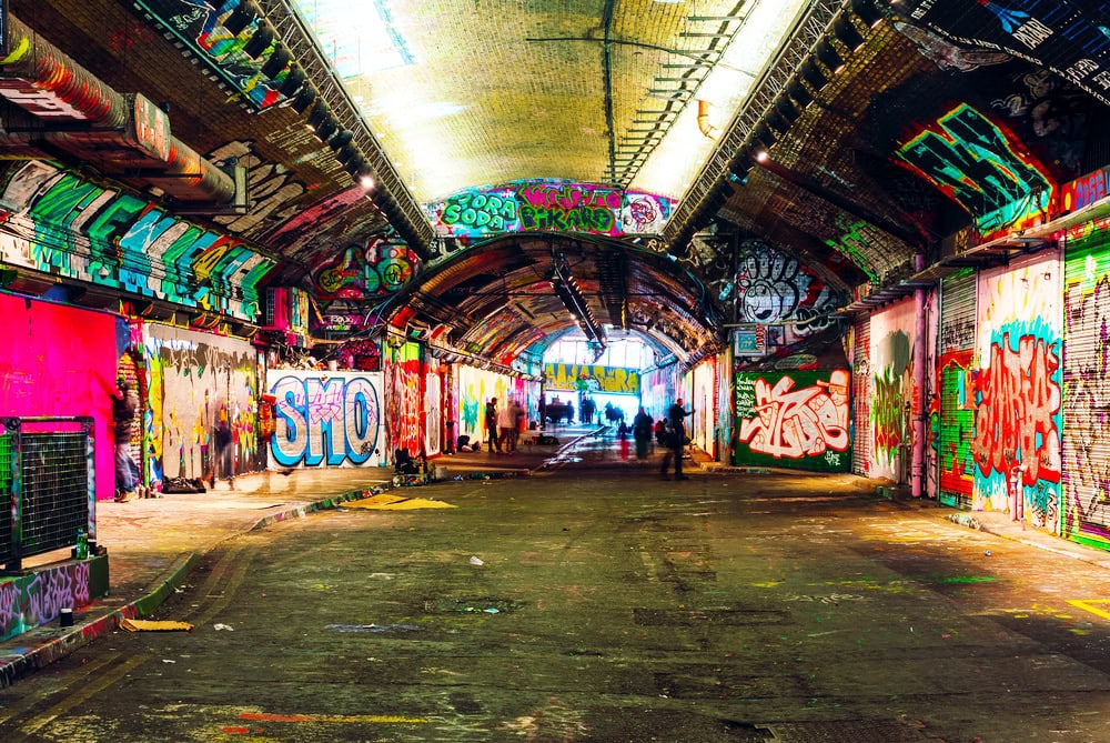 London, UK/Europe; 21/12/2019: Leake Street, underground tunnel with graffiti covered walls in London. Scene with pedestrians and graffiti artists.