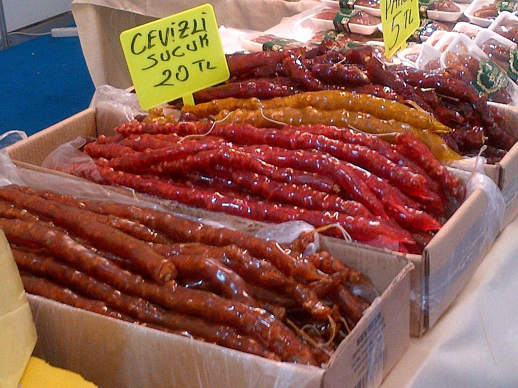 Cardboard boxes are filled with rows of long, cylindrical, nut-filled treats in shades of red, brown, and yellow.