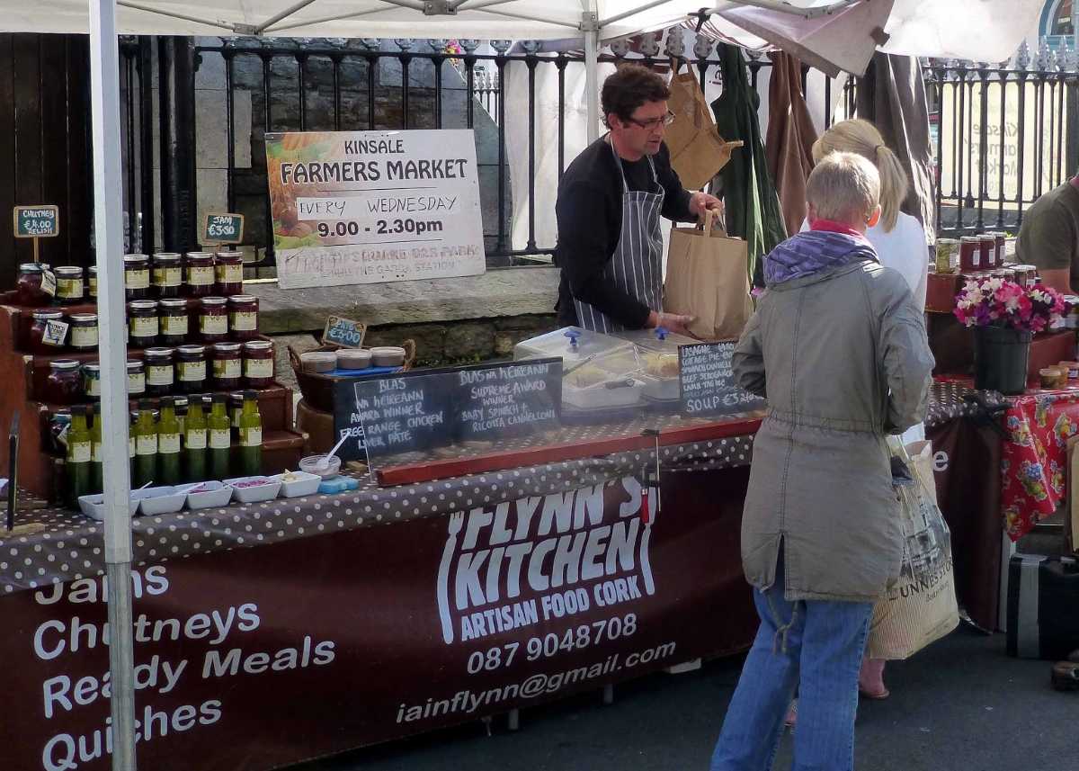 Food booth at the Kinsale Farmers market under a white canopy with a display of jams