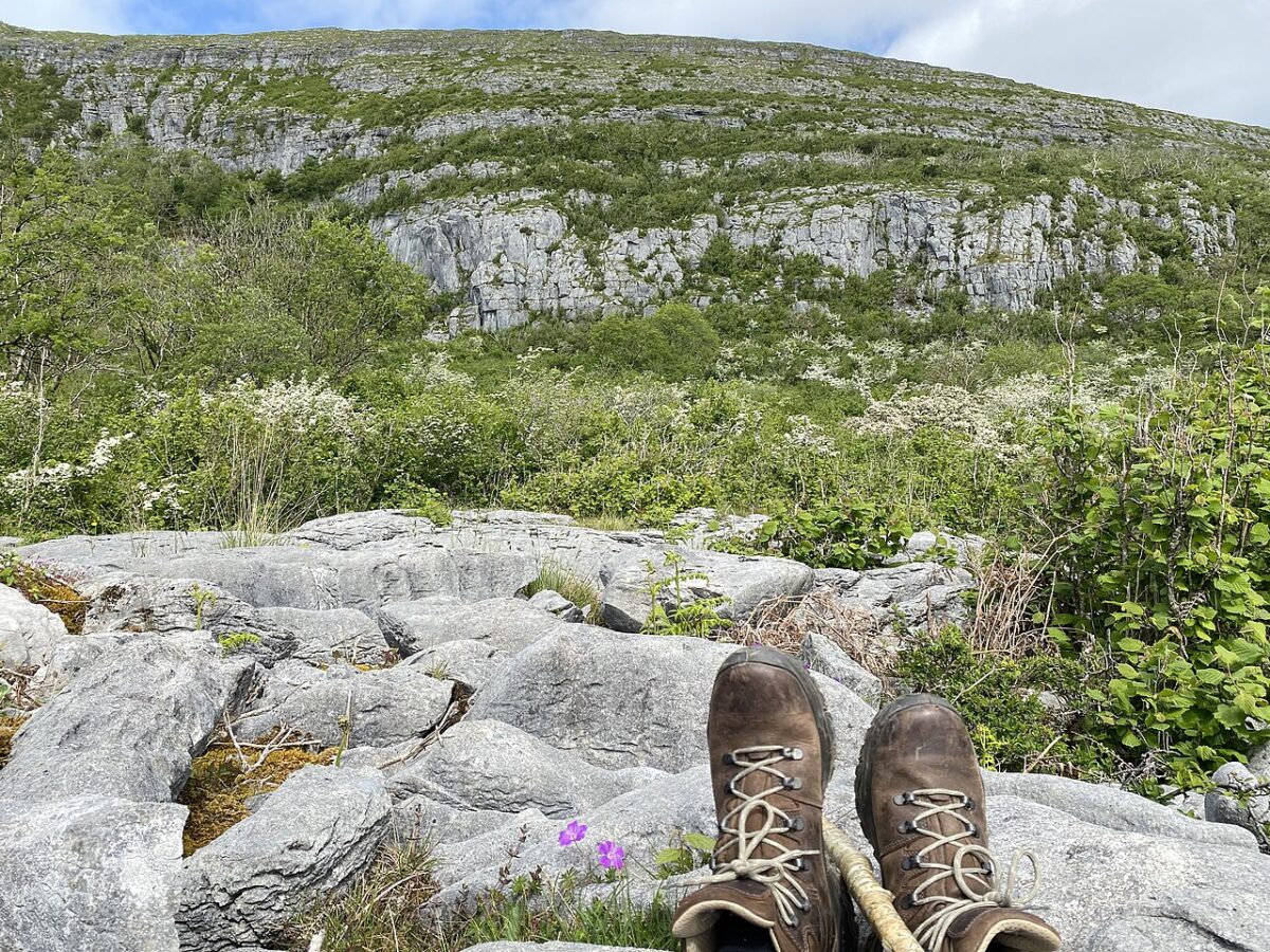 Climbing slieve Carran, Eagles Rock a person sits on the rocks but you can only see the rocks, the hills and hiking boots