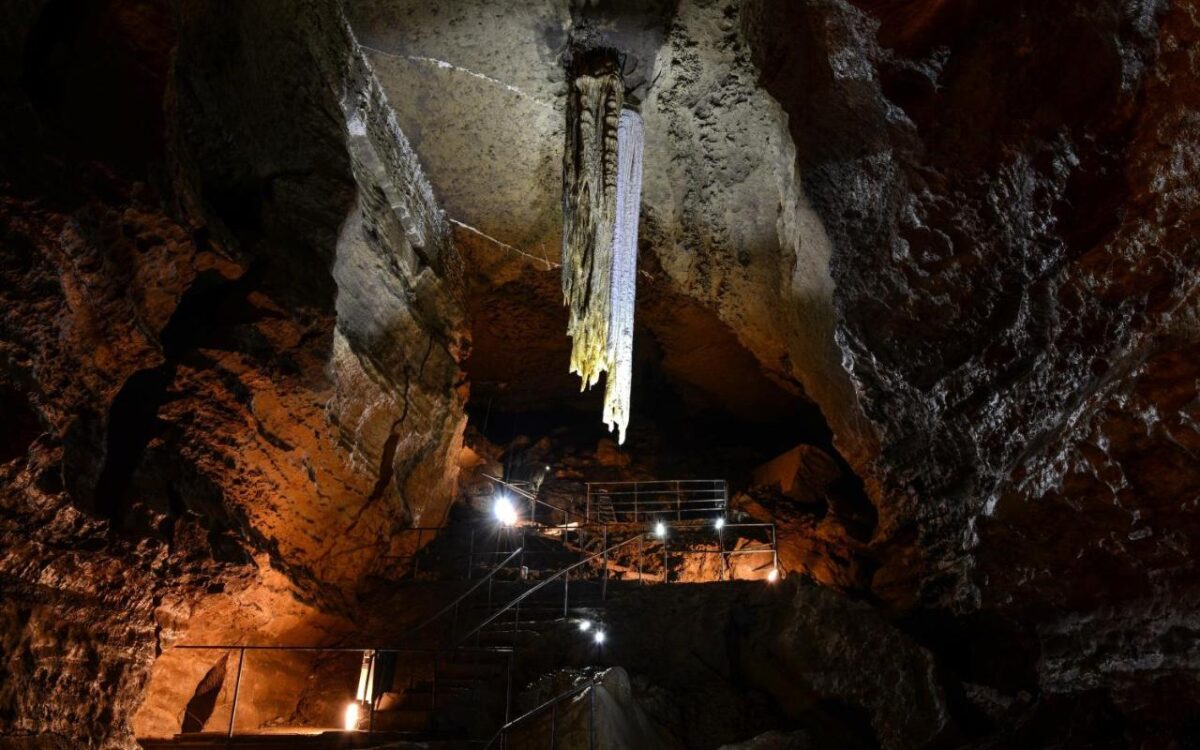 Aillwee Cave lit by golden lights so you can see the stalactites in the Burren