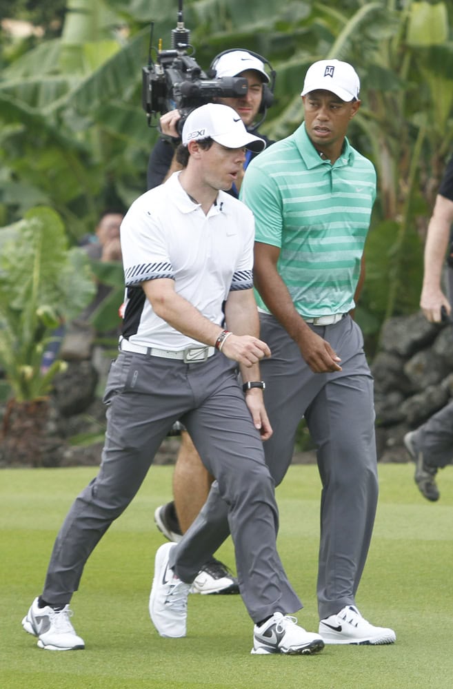 Rory McIlroy of Northern Ireland, left, and Tiger Woods of the United States, right, walk to play their next shots