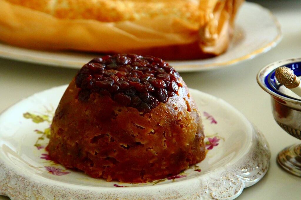 a rounded pudding on a plate stuffed with fruit and dried fruit on top 