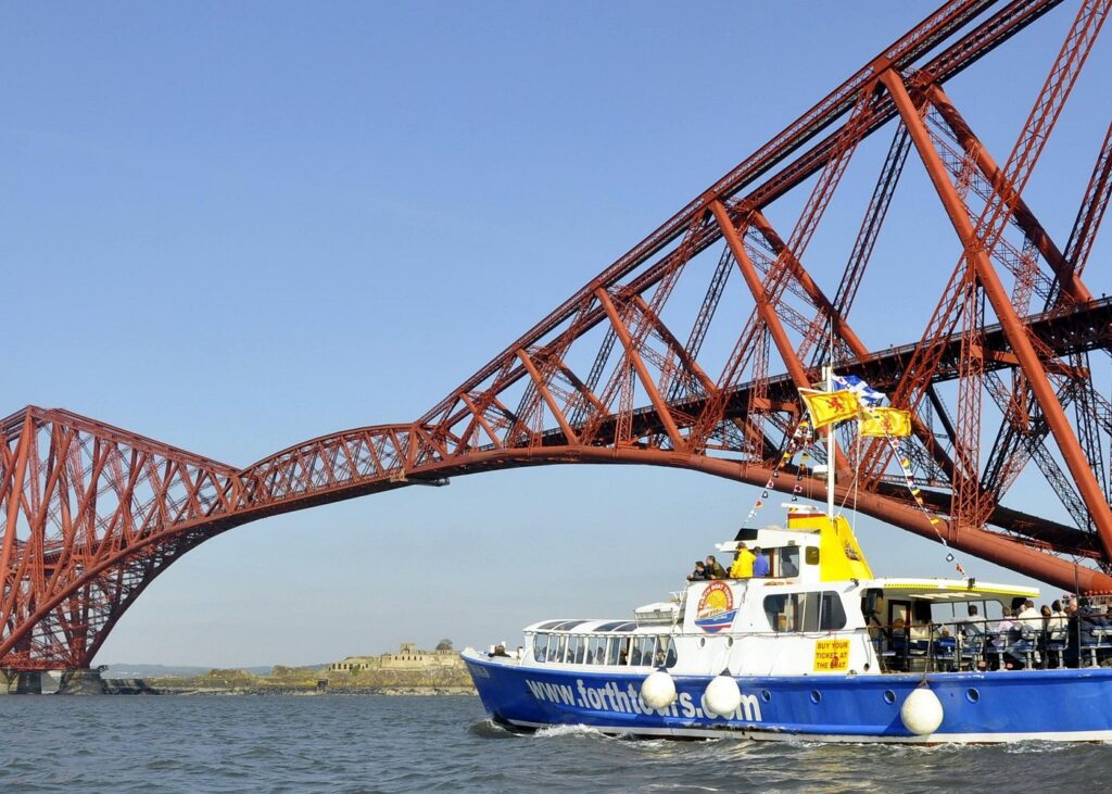 A tour boat passes under the great iron bridge of the Firth of Forth
