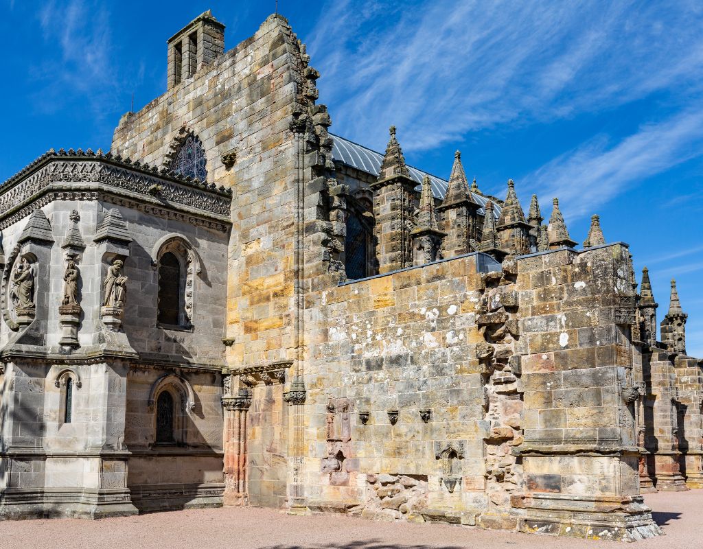 Rosslyn Chapel, located in Scotland, is a stunning 15th-century Gothic chapel renowned for its intricate stone carvings, including elaborate foliage patterns, intricate arches, and mysterious symbolic figures, all set within a compact, atmospheric structure with a richly decorated interior and a sense of historical and mystical allure.