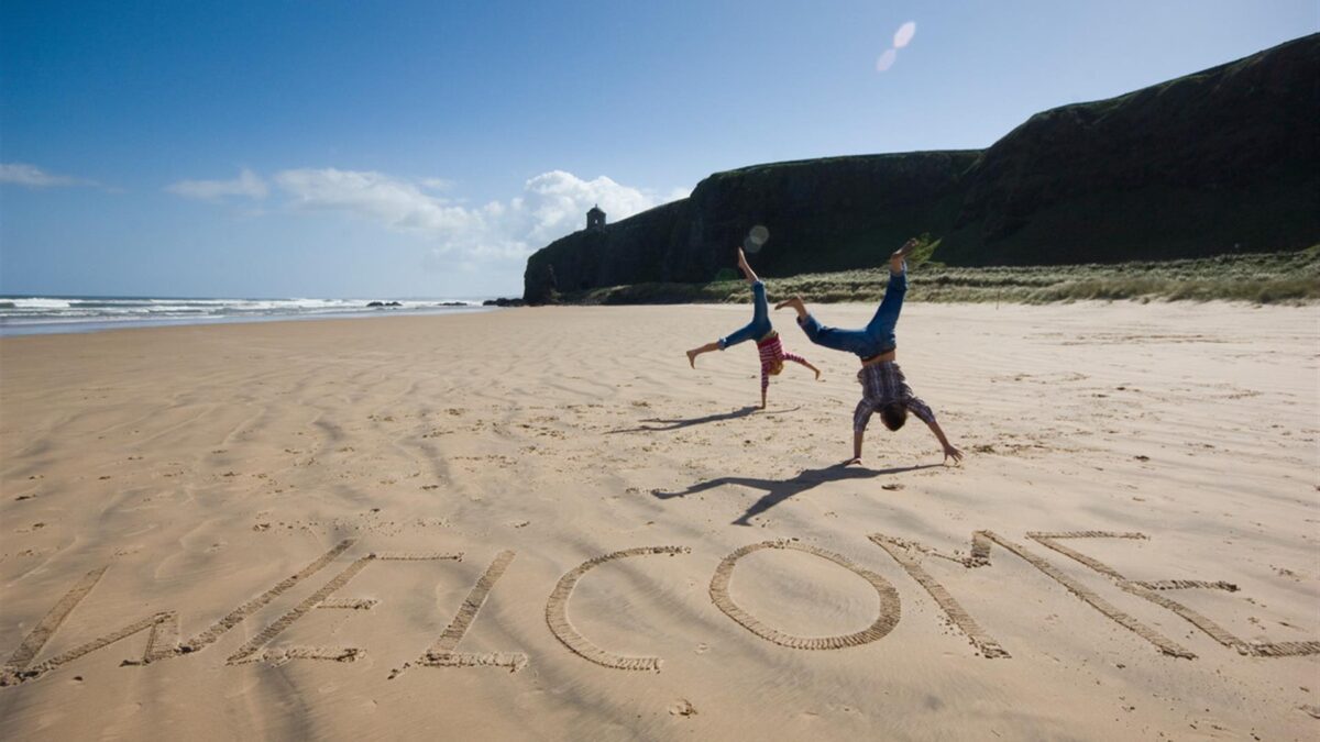 Benone Strand a yellow sand beach in County Derry with children doing cartwheels on the beach