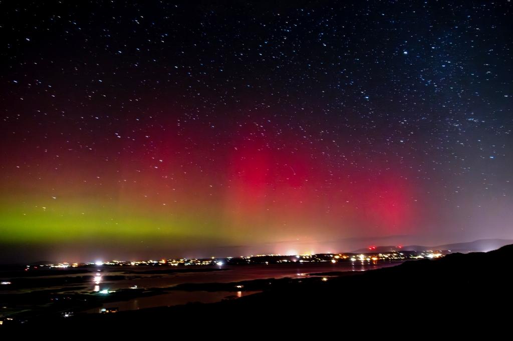 The Northern lights shine above the village of Portnoo in Donegal. The lights ae bright red, pink and run into yellow and green