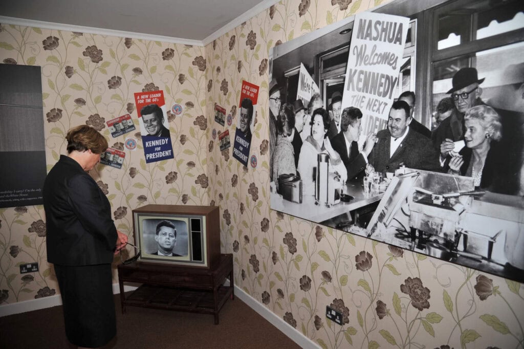 A living room of the Kennedy homestead recreated for tourists with a small black and white tv and posters on the walls