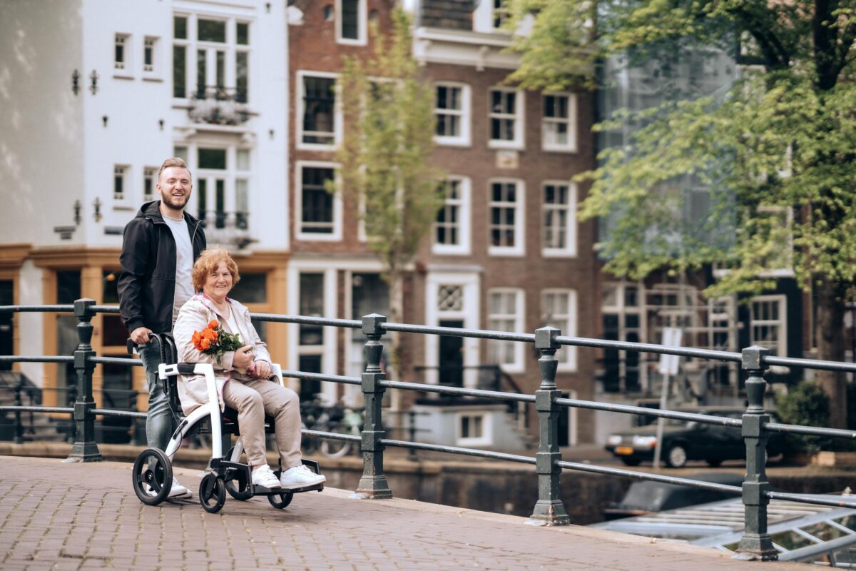 A senior woman in a wheelchair with flowers enjoys a stroll along Amsterdam's iconic canals.