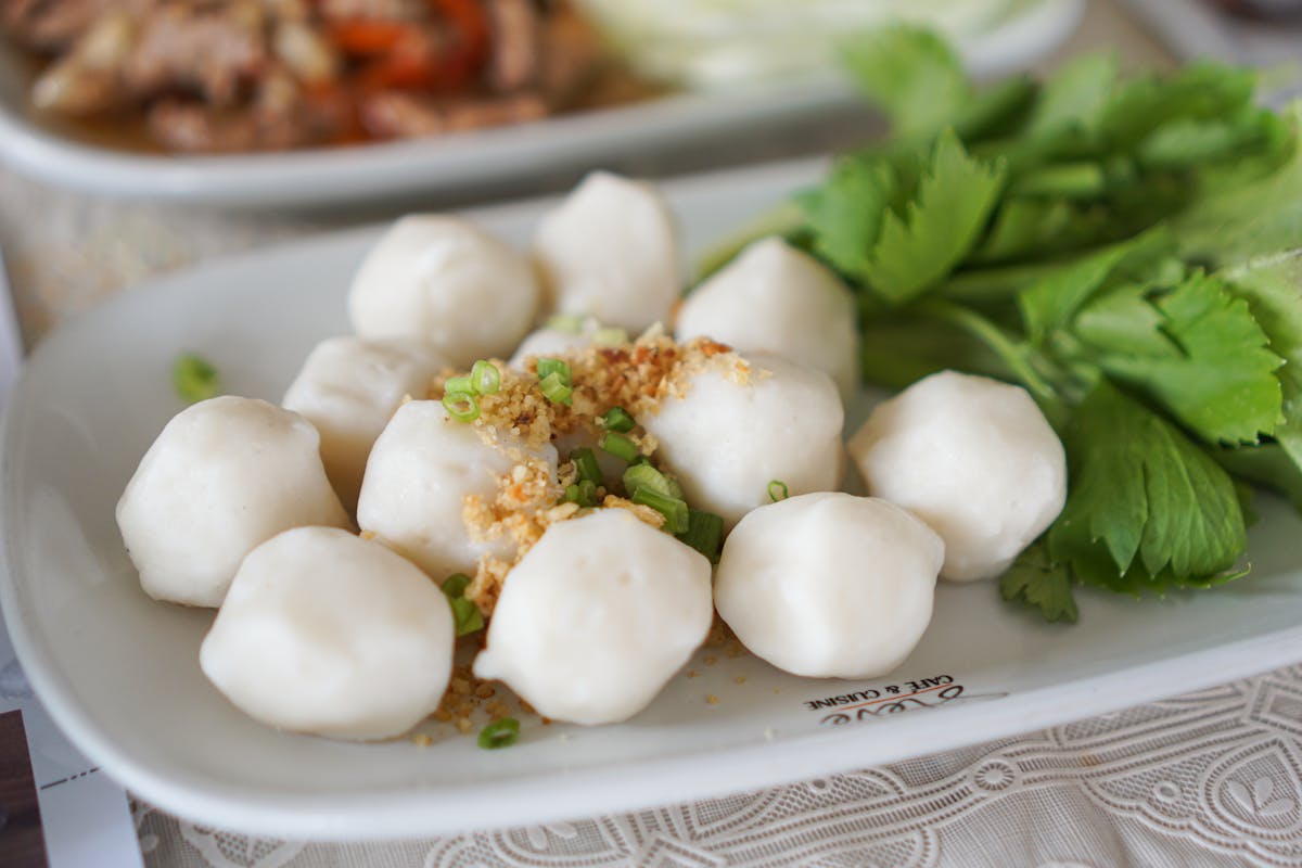 Close-up of savory fish balls garnished with parsley on a ceramic dish, perfect for food photography.