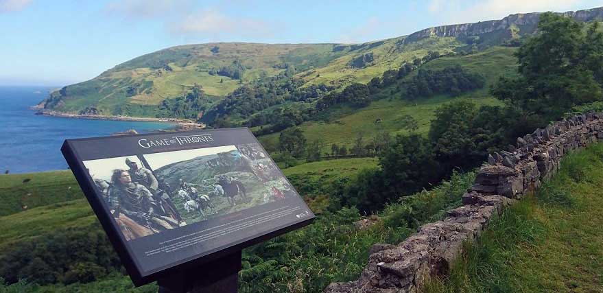 Game of Thrones sign overlooks green hills and the ocean.