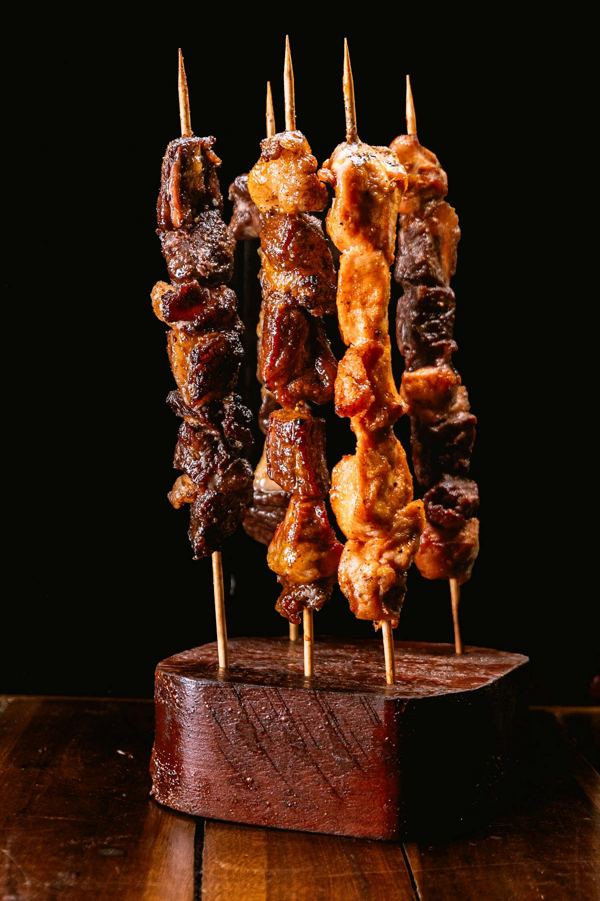 Savory grilled meat skewers displayed on a rustic wooden stand.