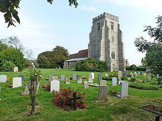 A stone church with a square tower stands behind a grassy graveyard filled with numerous headstones.