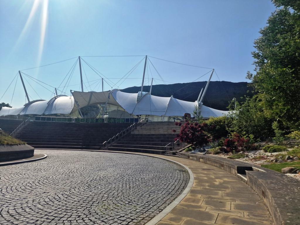The domed science centre that sits in front of a massive Calton Hill behind it and has white canvas type roof in Edinburgh