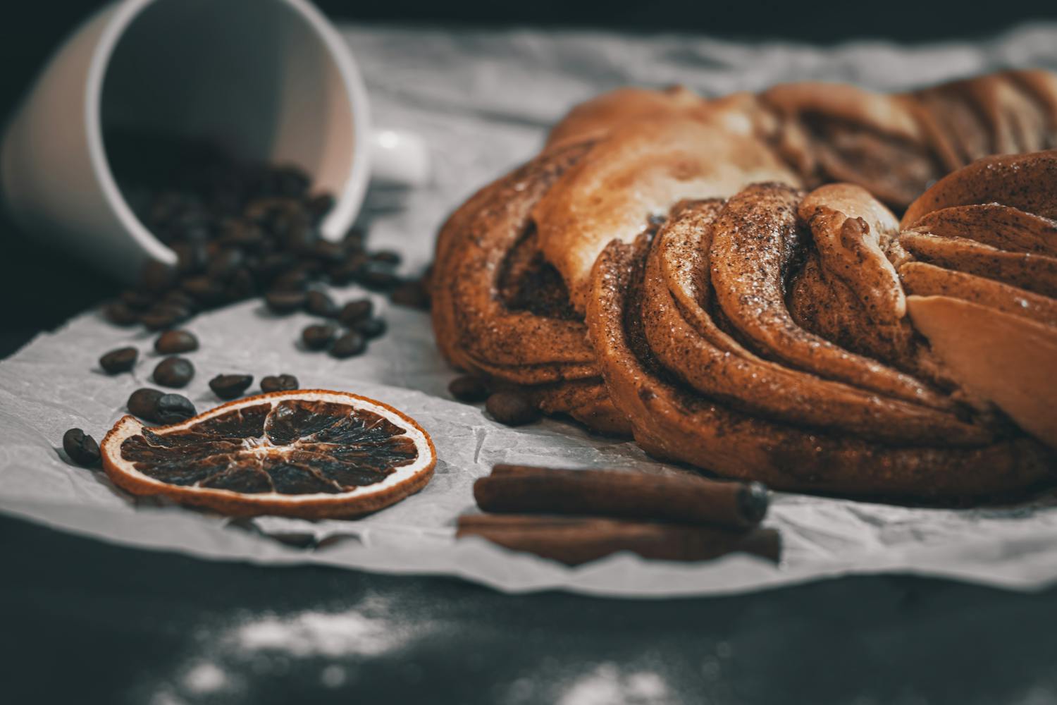 Delicious cinnamon pastry with coffee beans and dried orange slice, perfect for cozy breakfasts.
