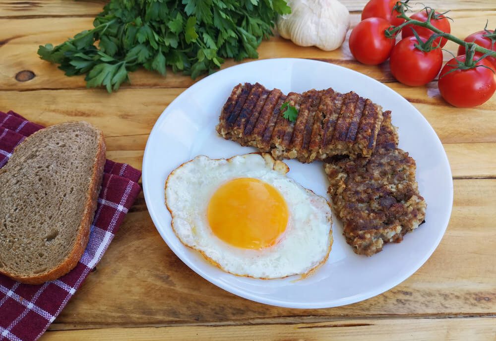 Breakfast with goetta and fried egg on plate (Cincinnati Breakfast Classic) on wooden table