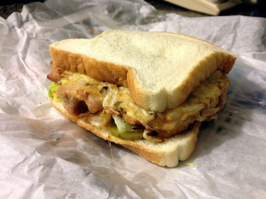 An egg foo yung patty sandwiched between two slices of white bread