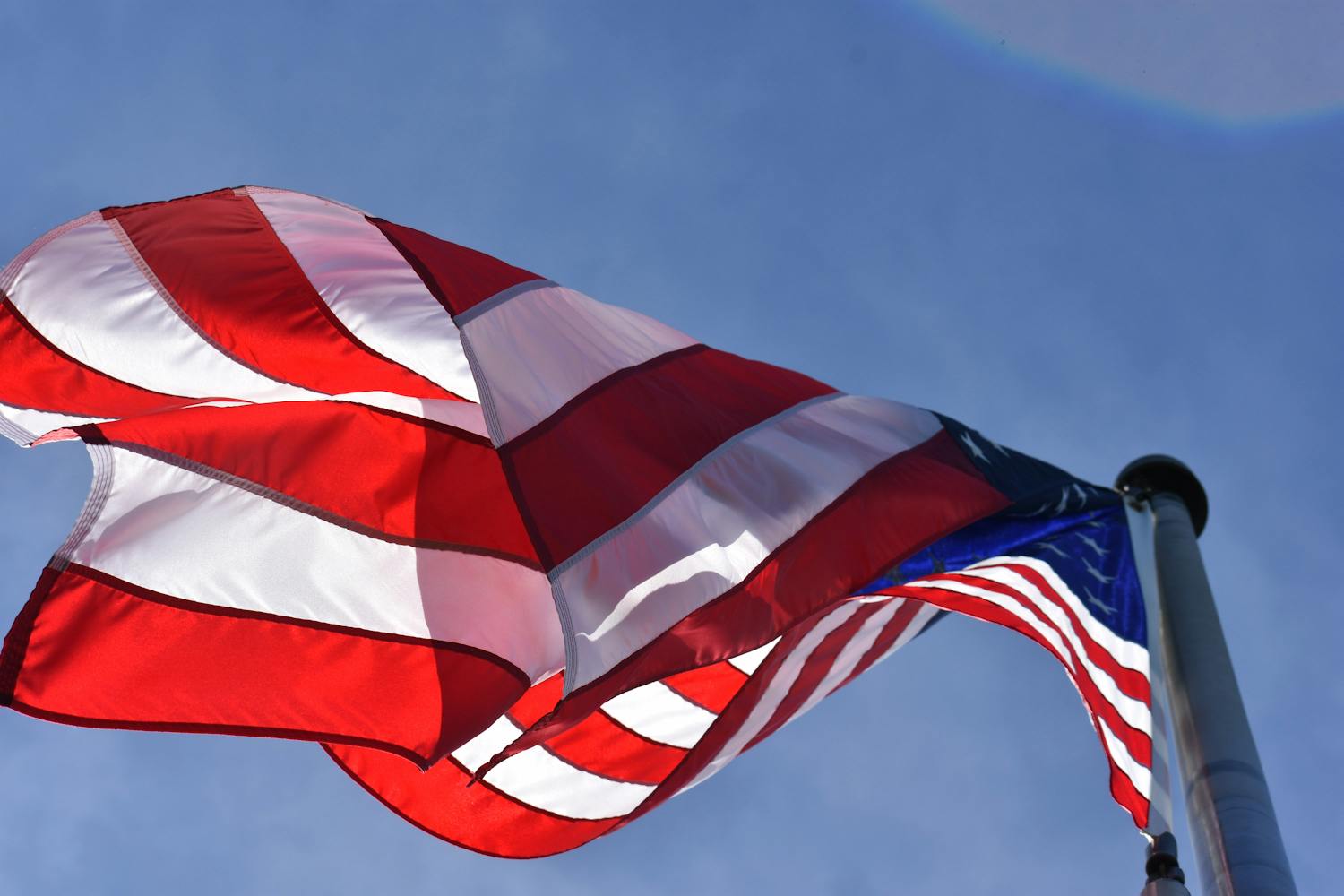 Close-up of a waving American flag under clear blue skies,