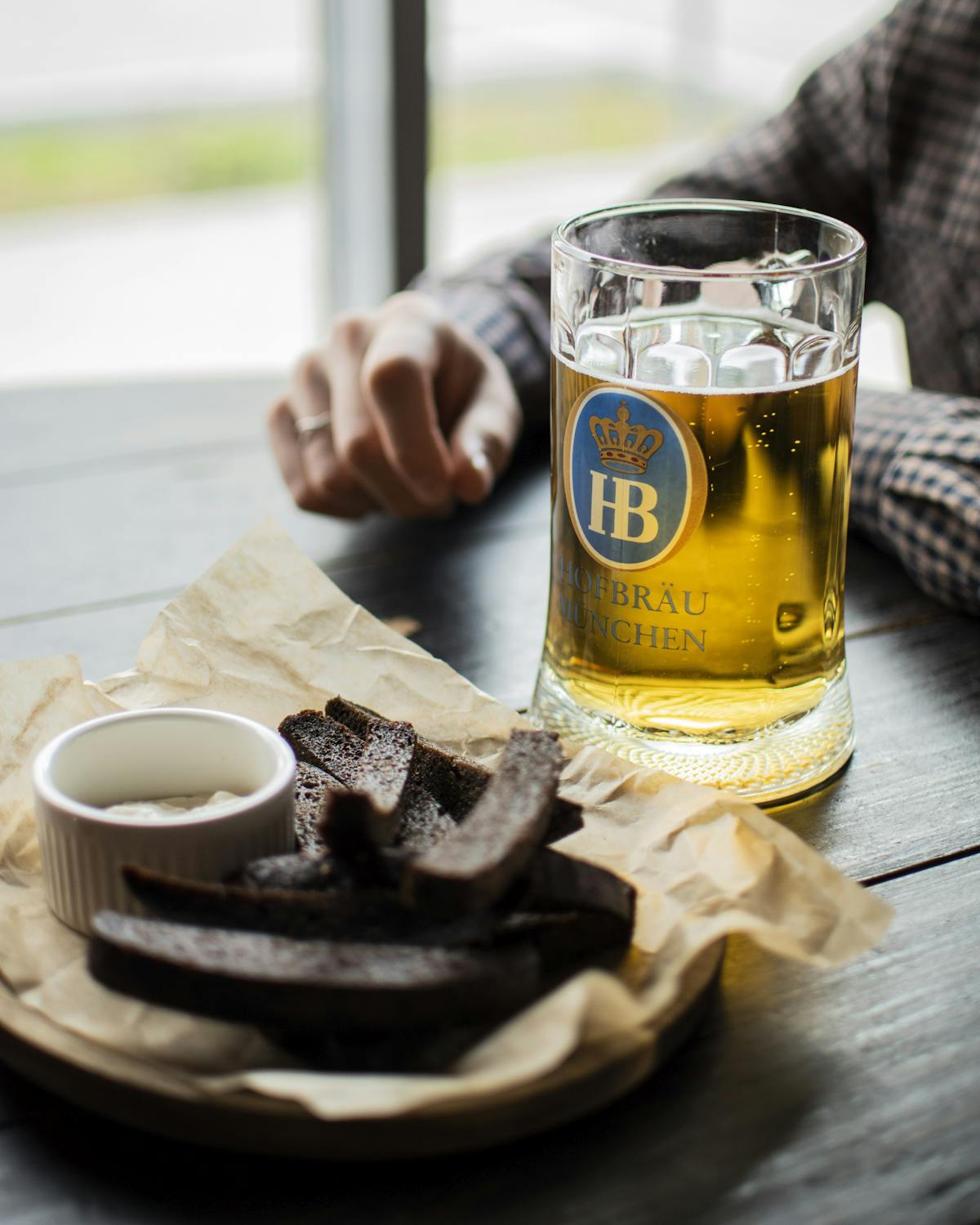 A glass of beer and rustic bread on a pub table, evoking a cozy dining experience.