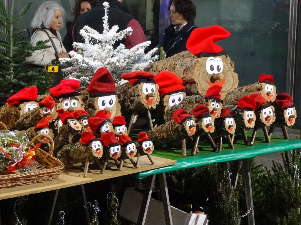 A table displays many small log figures with cartoon faces and red hats, with people standing in the background.