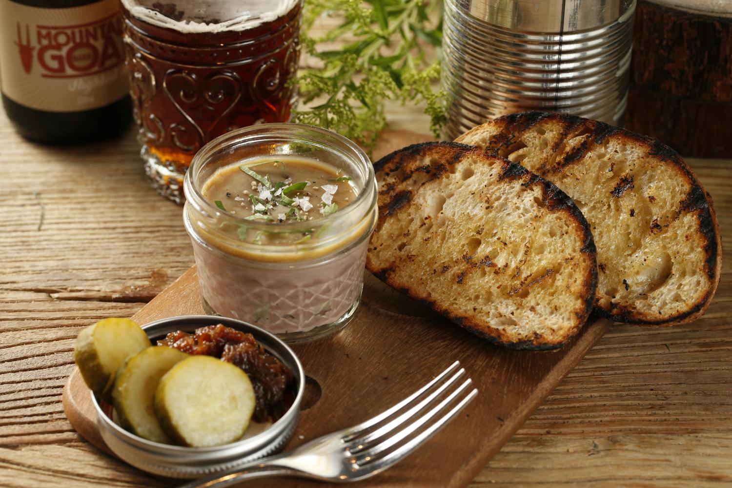 Delicious pate served with pickles and grilled bread on a wooden table, perfect for food enthusiasts.
