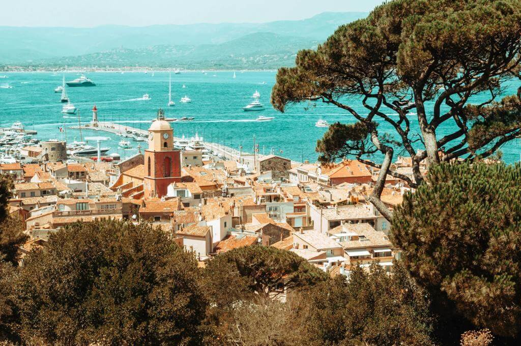 Harbour view of Saint Tropez with red roofed houses and a turquoice blue sea