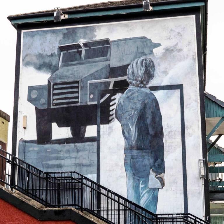 Saturday Night Mural in Derry shows a boy with a rock facing a police vehicle