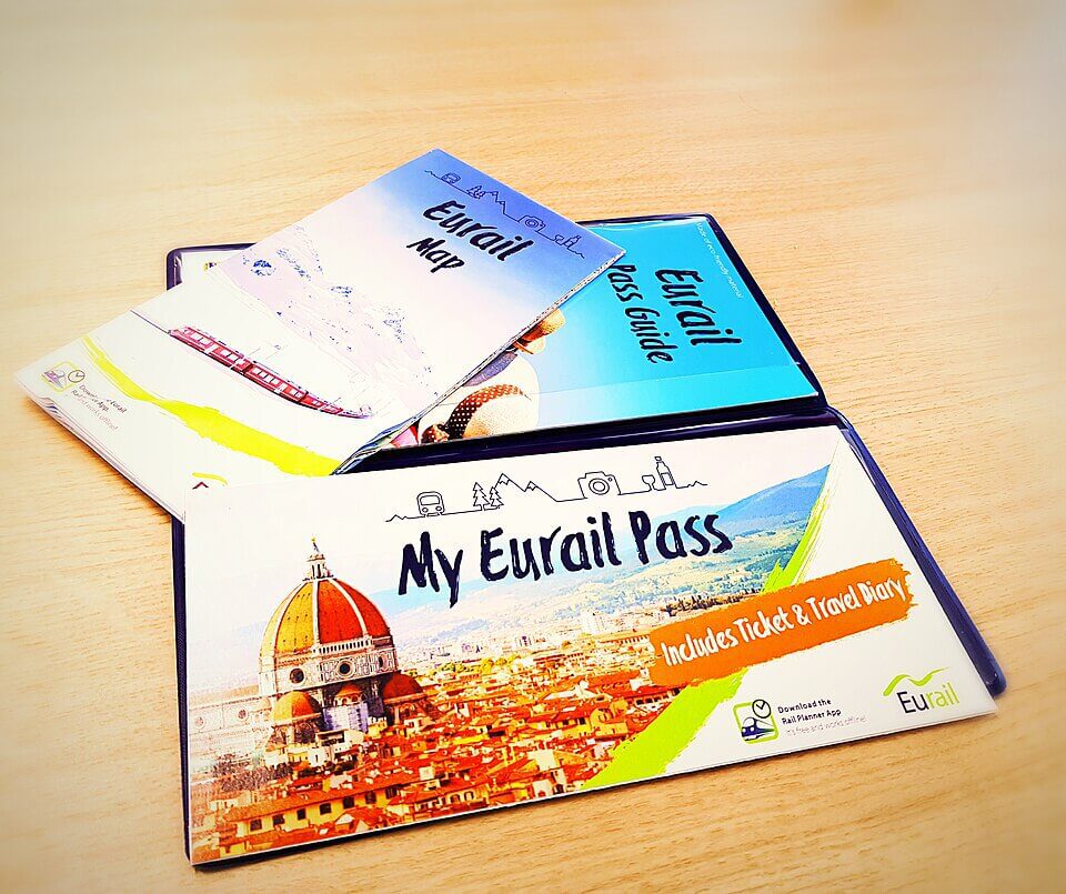 A Eurail pass and guide sits on a wooden table