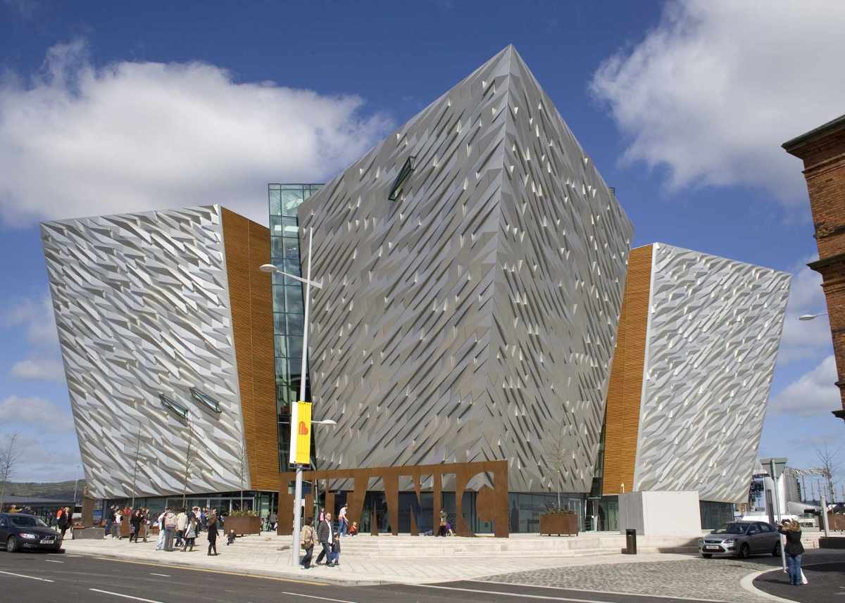 Titanic Belfast, a striking museum with angular metallic panels, stands under a blue sky in Northern Ireland.