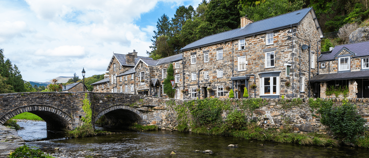 Prettiest town in Wales Beddgelert with a river and curved arched bridge running beside stone cottages