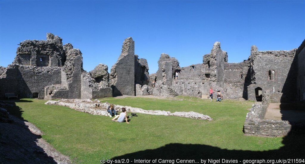 the romantic ruins of Carreg Cennen Castle in Wales with two people having a picnic inside the castle walls
