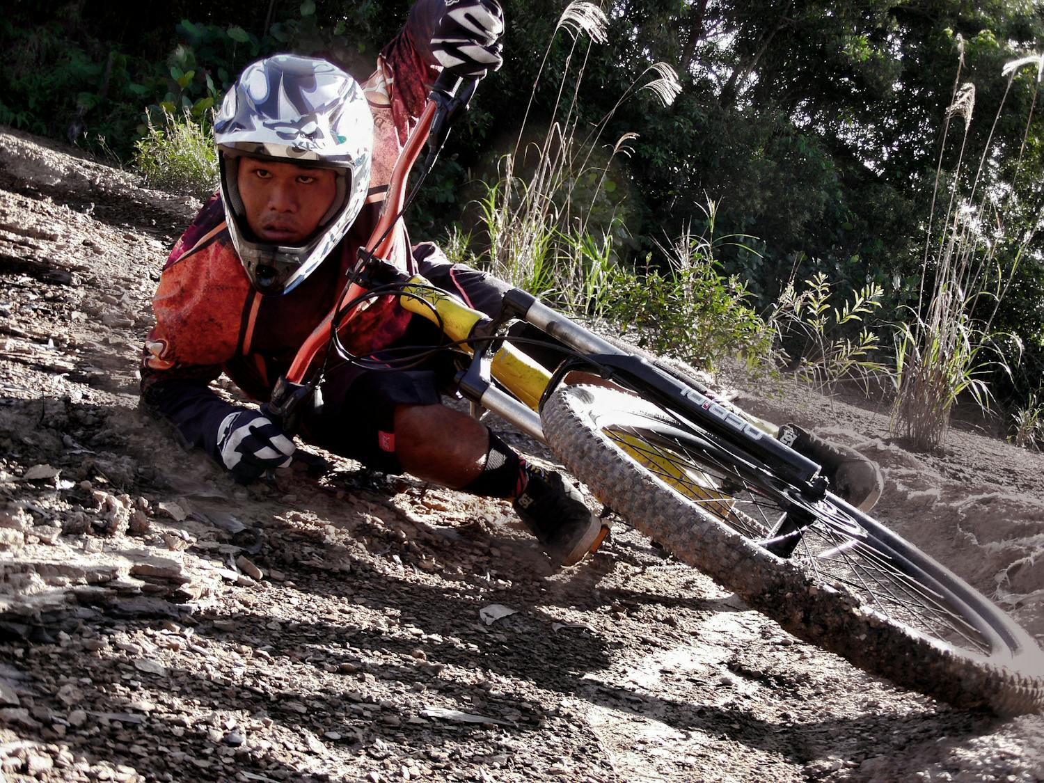 Close-up of a cyclist crashing on a dirt mountain bike track, showing action and speed.