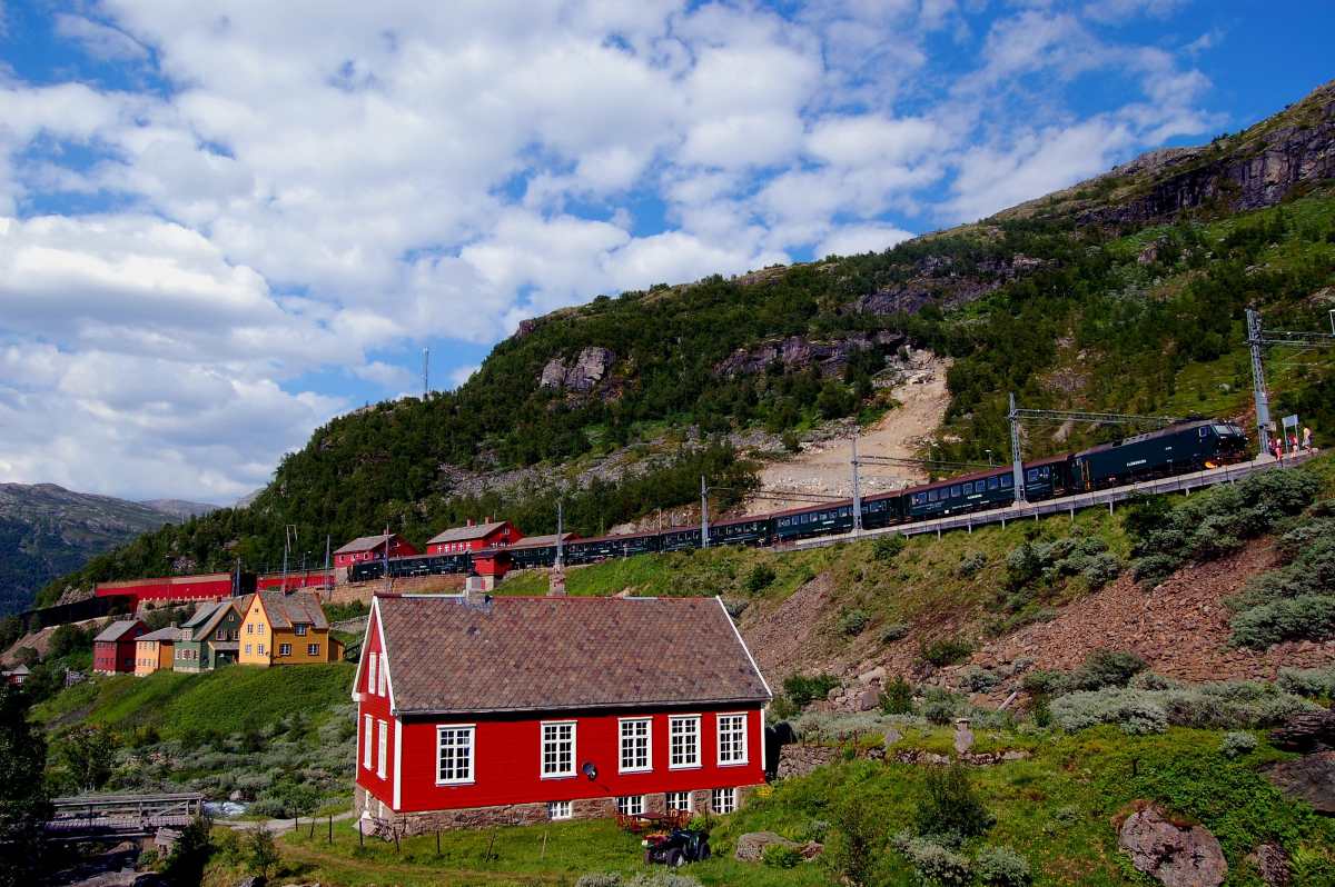 Flam train norway passes behind a village and up a mountains
