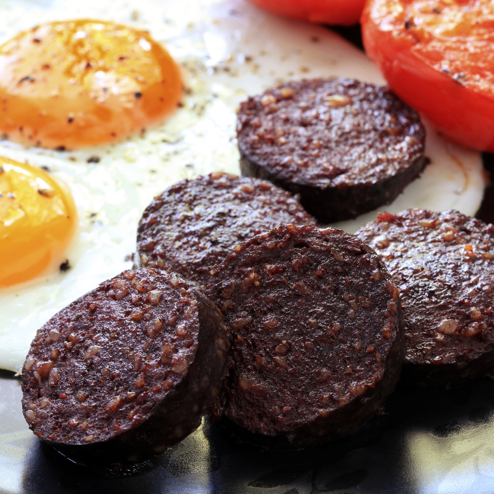 A plate of black pudding with eggs and tomatoes