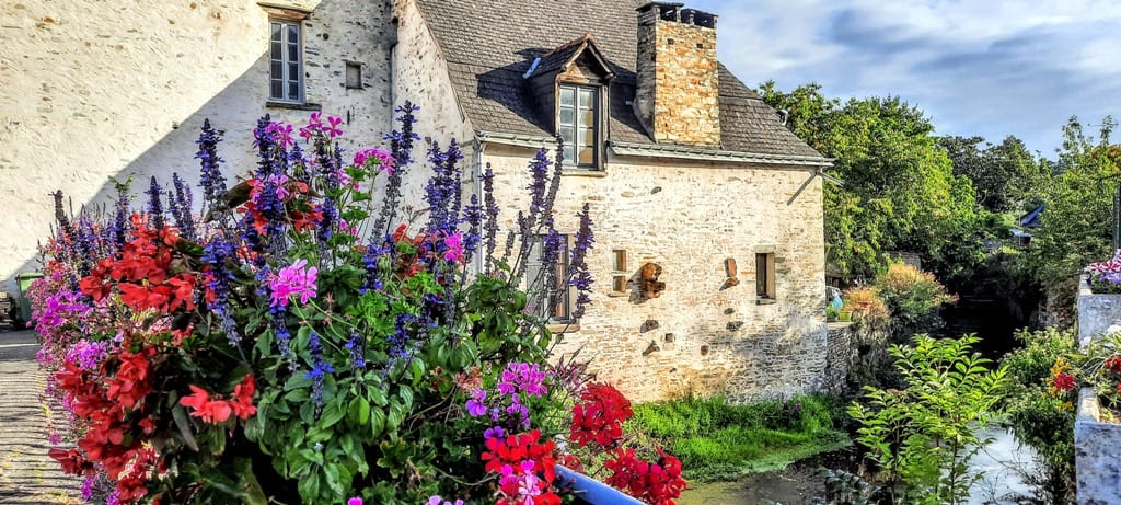Stone house decorated with baskets of colourful flowers in the Mayenne France