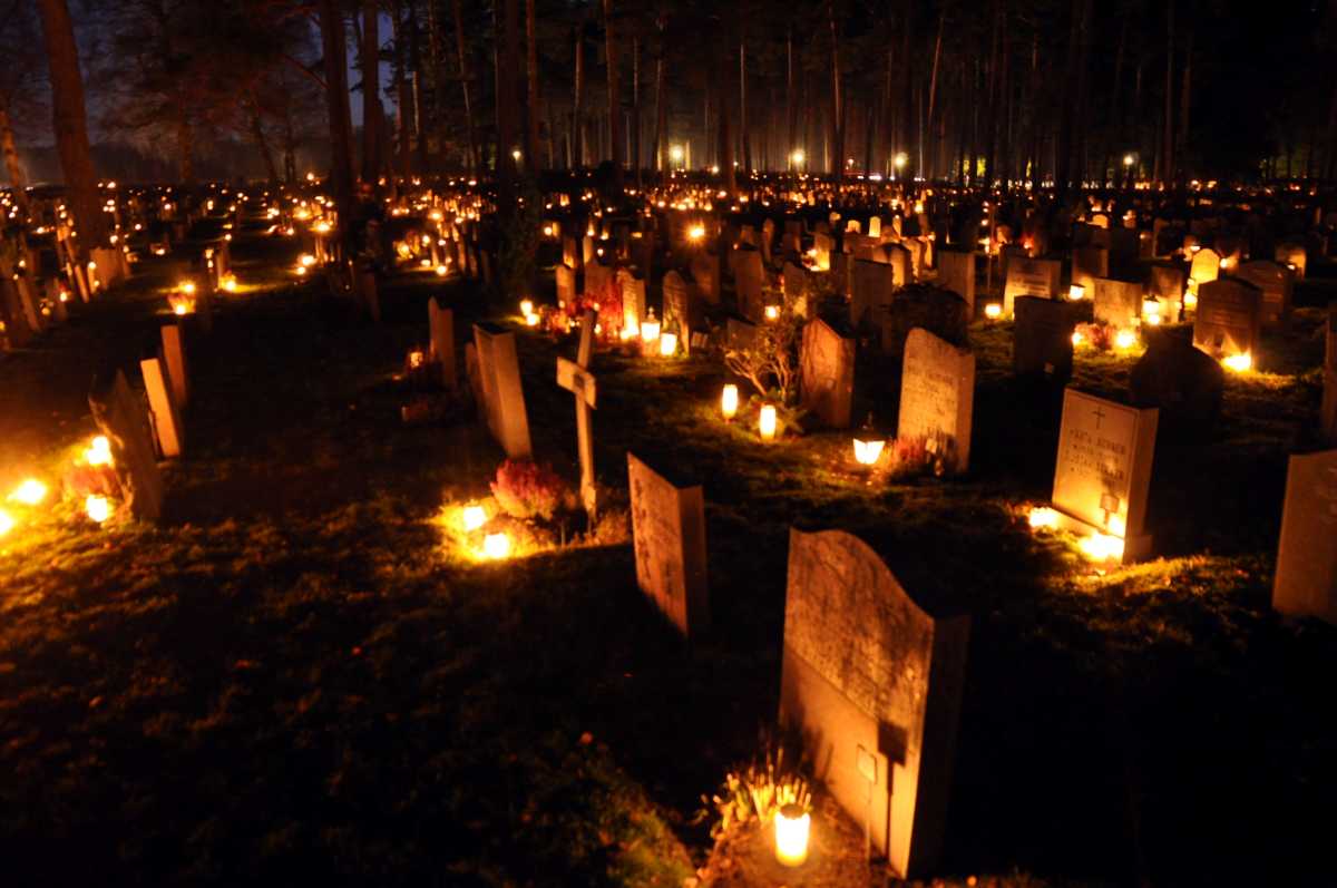 hundreds of candles on graves at night.