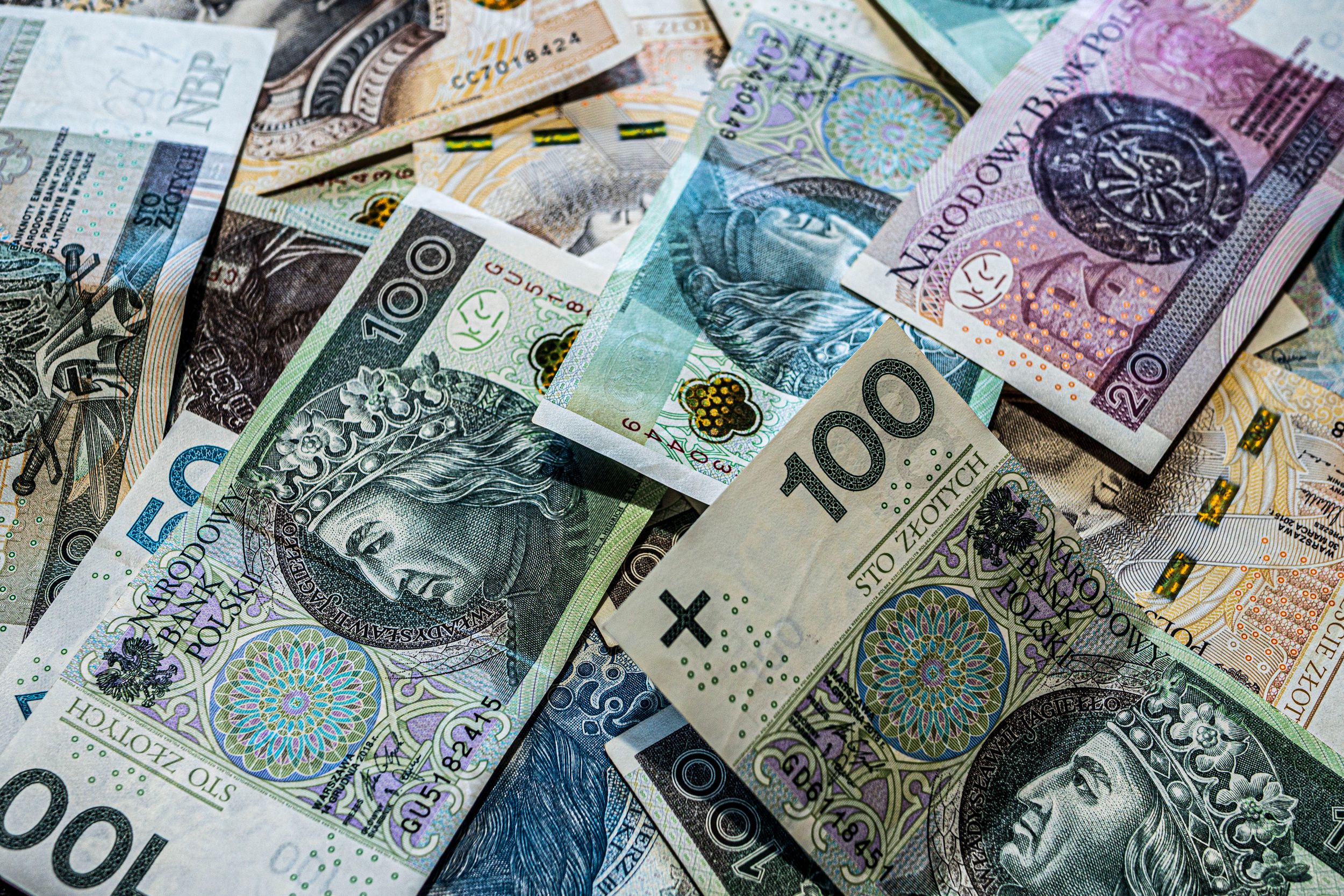 A collection of Polish Zloty banknotes in various denominations, scattered.