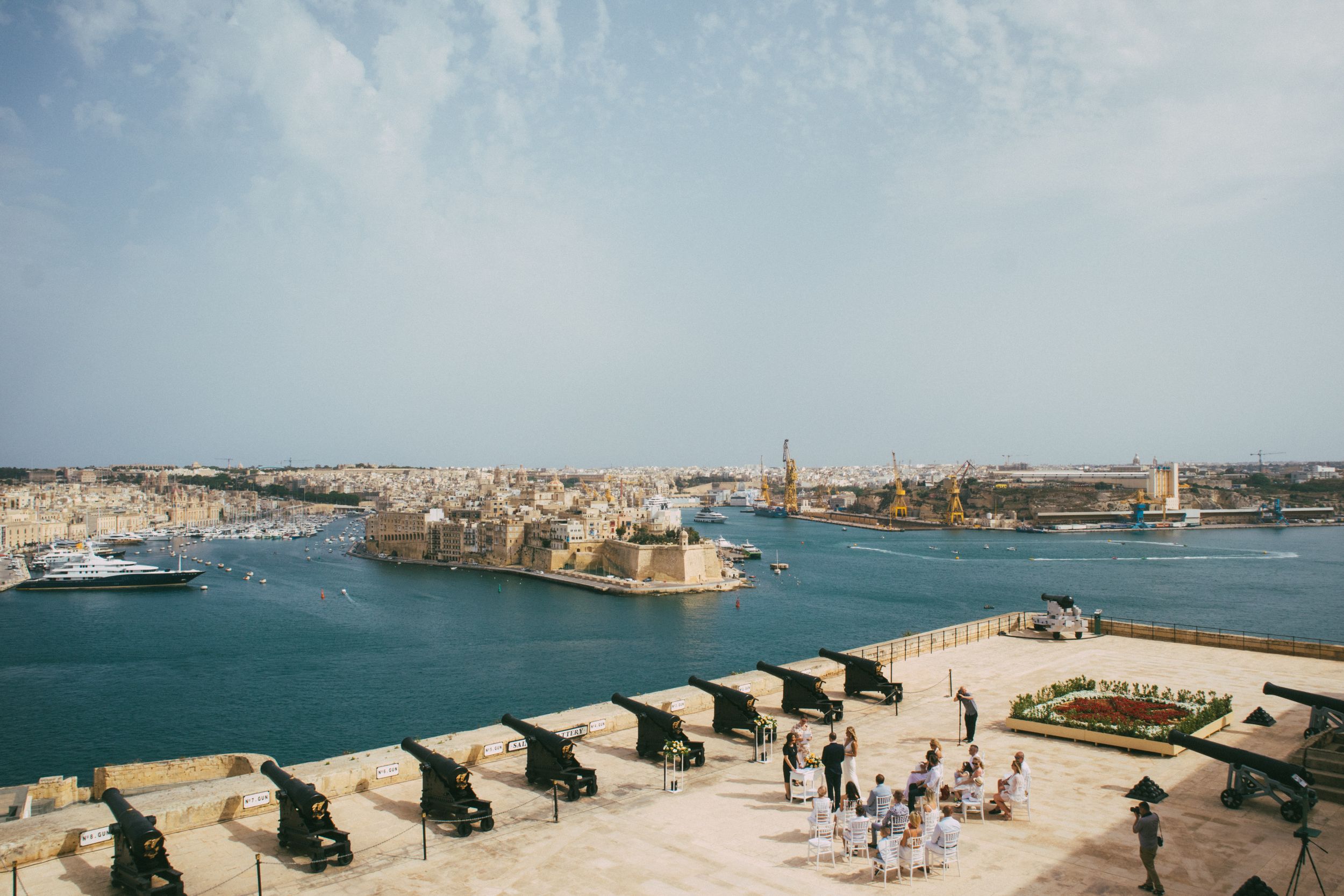 Aerial view of Valetta Harbor from Upper Barrakka Gardens with historical cannons and yachts.