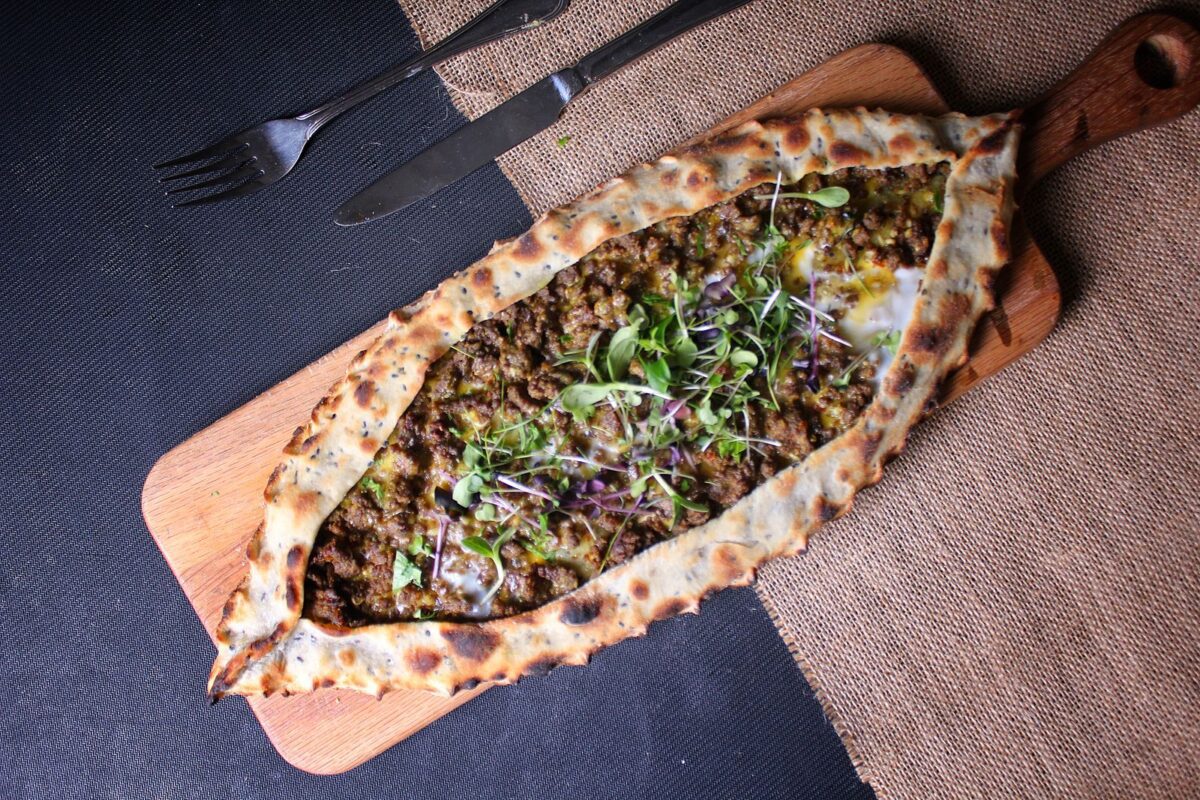 Delicious Turkish pide topped with vegetables and fresh herbs on a wooden board. Zaatar is the main spice blend