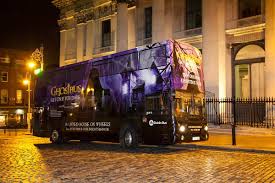 Dublin Ghostbus, a purple double-decker, parked at night in front of the Bank of Ireland.