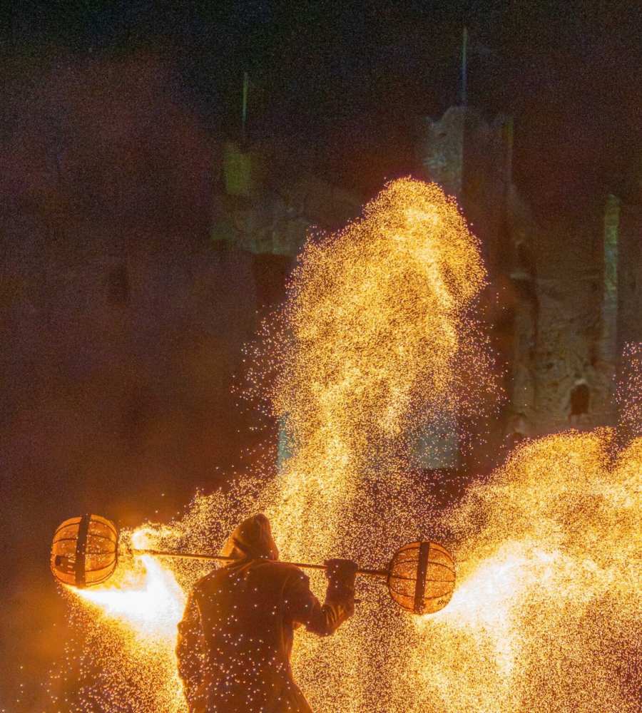 A fire performer creates a shower of sparks and flames in front of Bunratty Castle, Ireland.