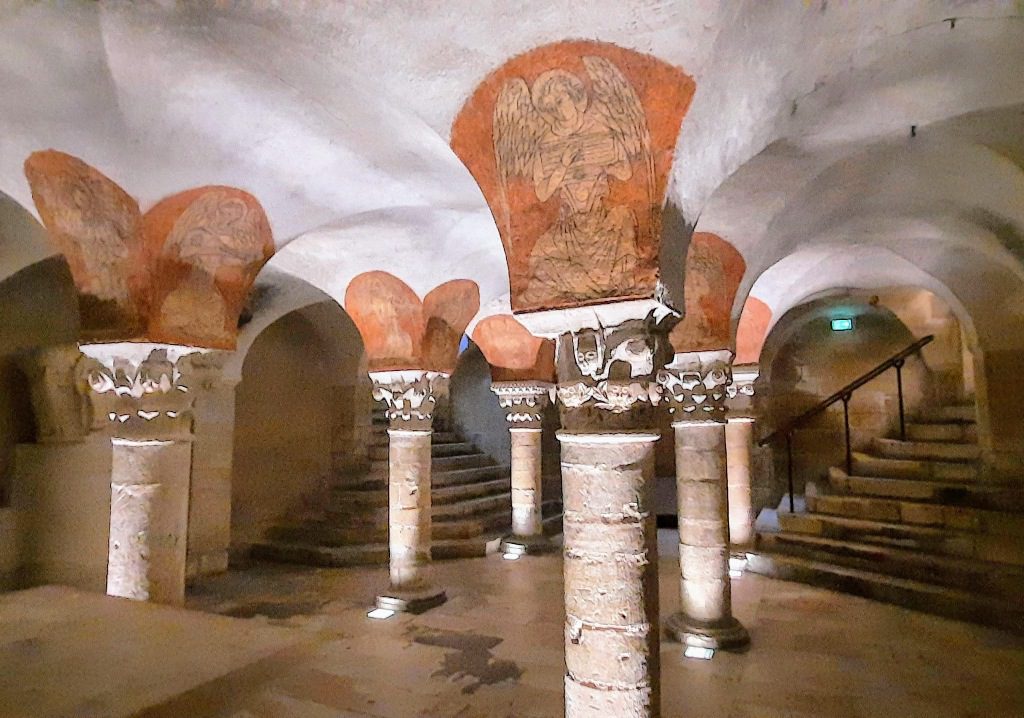 The Crypt of Saint-Germain dAuxerre features ancient columns, vaulted ceilings, and a prominent angel fresco.