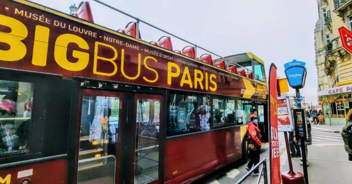 A Big Bus Paris tour bus, listing landmarks like the Louvre and Notre-Dame, is parked on a Parisian street. Best for Accessible travel Paris
