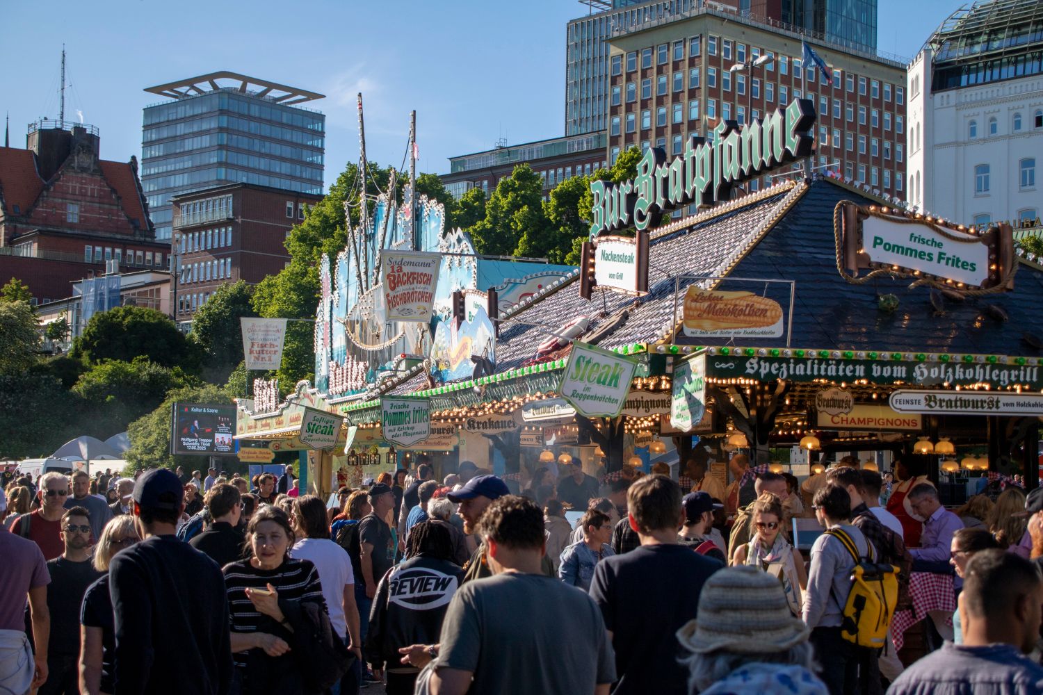 A bustling street festival in Hamburg with crowds enjoying food stalls under a blue sky.